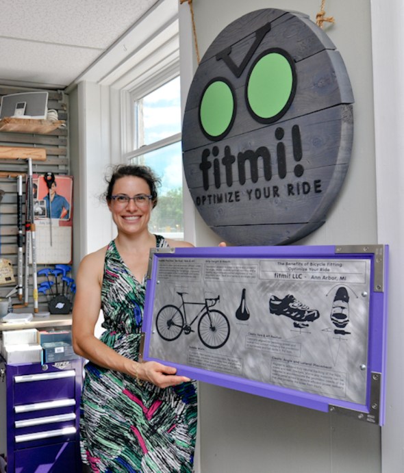 Fitmi! LLC Owner Jess, sporting two pieces of our work (wall sign and portable educational prop)